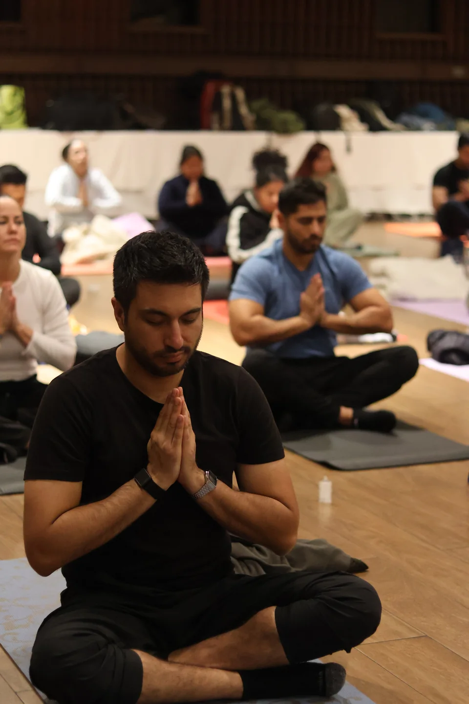 A seated participant with palms together and eyes lowered at a previous Resetea session
