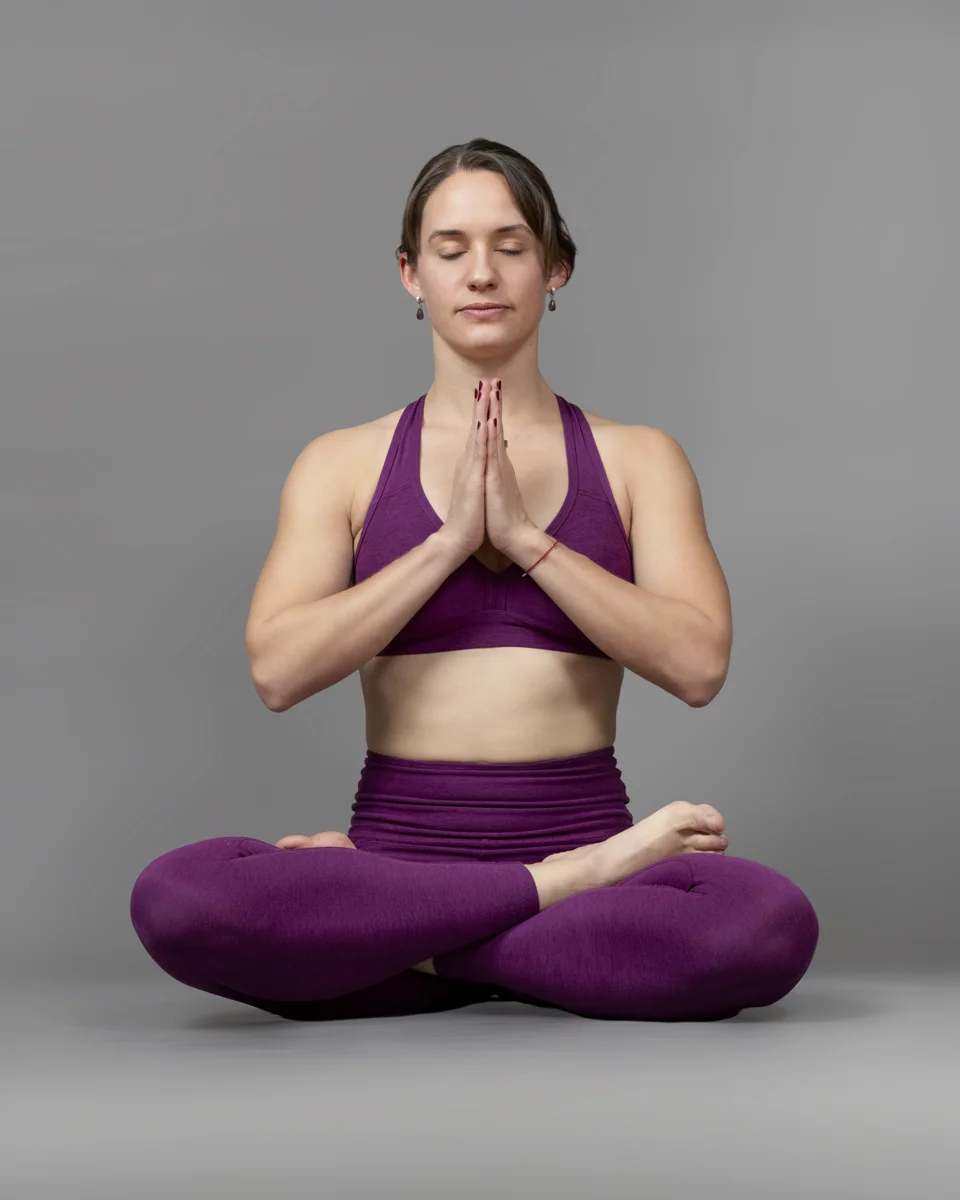 Sharon Broadway seated in a yoga pose with palms together